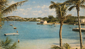 A tropical beach scene with turquoise water, palm trees, boats anchored near a shoreline, and a sunny, clear sky.