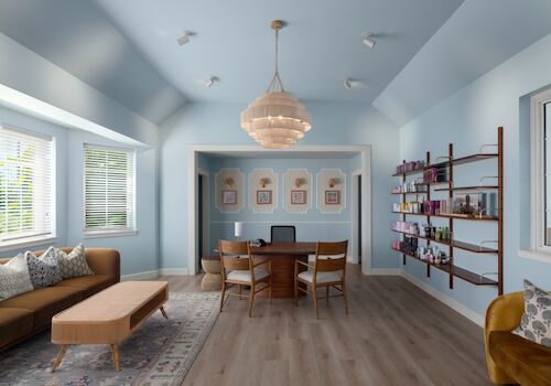 A bright modern lounge with a central dining table, chairs, pendant chandelier, sofa, rugs, and built-in shelves of books.