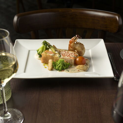 A plated gourmet entr&eacute;e with vegetables&mdash;broccoli, cherry tomatoes, and asparagus&mdash;served with a piece of meat and sauce.