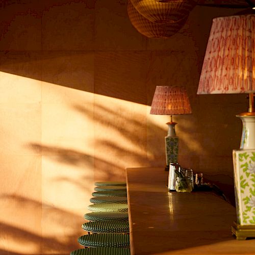 A cozy bar setup with green stools, a wooden countertop, and warm lighting from lamps placed on the counter.