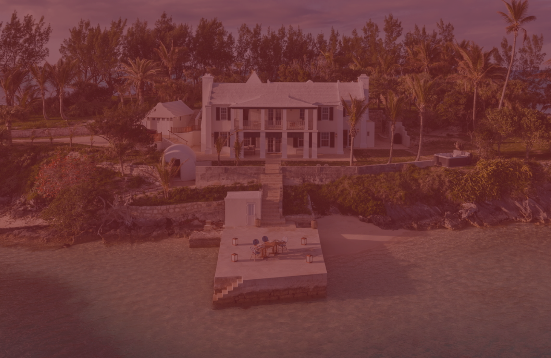 A luxury waterfront mansion on stilts with a private dock, tropical trees, and a calm lagoon setting, bathed in warm sunlight.