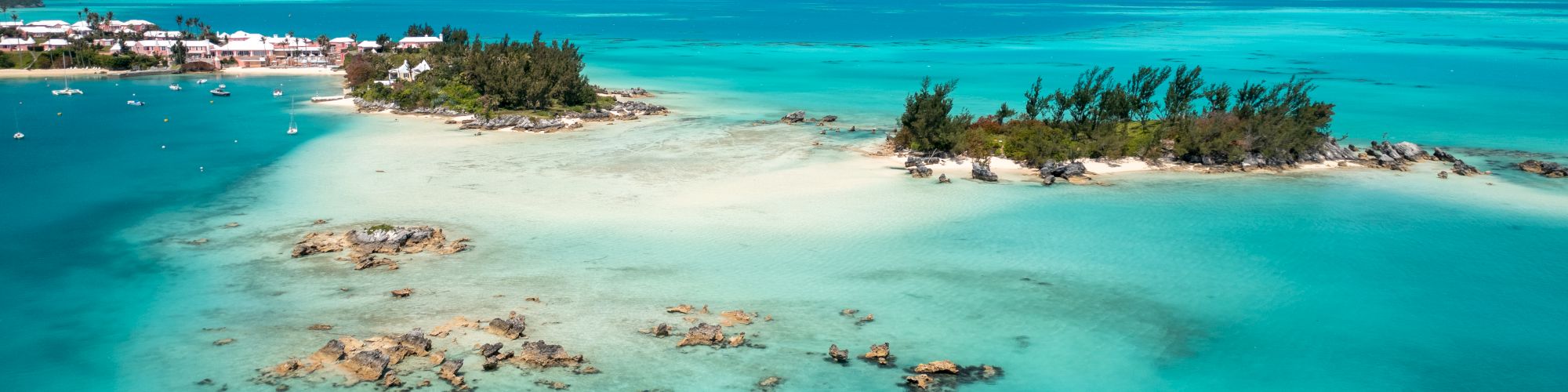 Aerial view of a picturesque island with turquoise water, sandy beaches, and lush greenery under a clear blue sky, perfect for a tropical getaway.