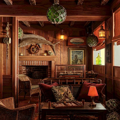 A cozy, rustic living room with wooden beams, wicker furniture, warm lighting, and decorative items such as a marlin mount and nautical-themed decor.