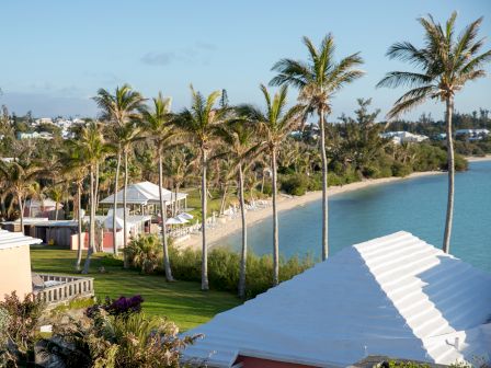 The image shows a scenic coastal area with palm trees, beach, and charming pastel-colored buildings under a clear blue sky, ending the sentence.