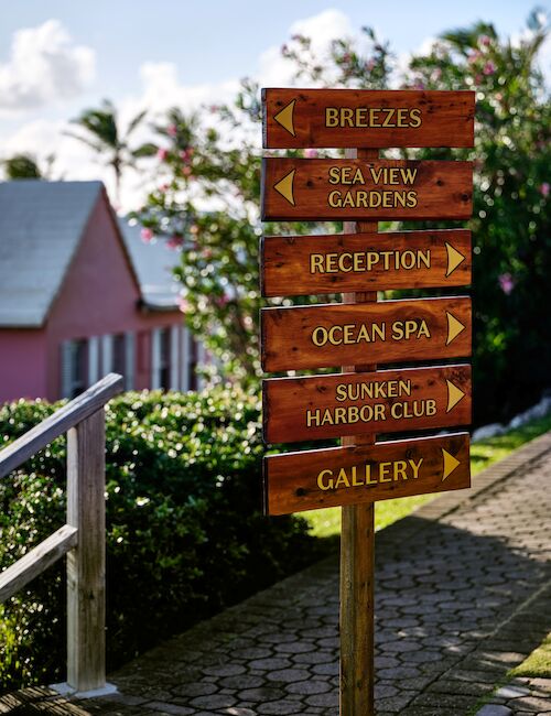 The image shows a directional signpost with arrows pointing to Breezes, Sea View Gardens, Reception, Ocean Spa, Sunken Harbor Club, and Gallery.