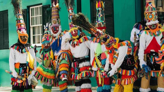 A group of people in colorful costumes and masks are gathered together, likely participating in a cultural festival or celebration.