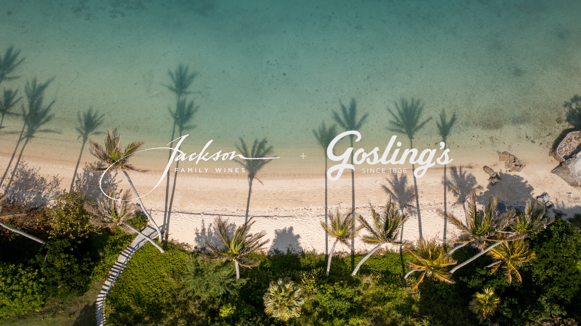 Aerial view of a beach with palm trees and clear water, featuring logos for Jackson Family Wines and Gosling's since 1806.