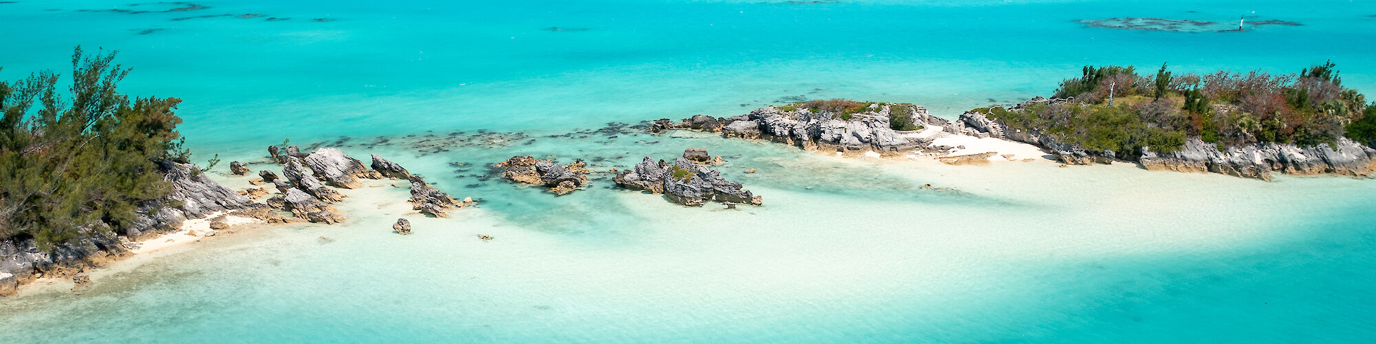 Aerial view of two jet skis riding in clear turquoise waters near a small island with rocky shores and sparse vegetation.