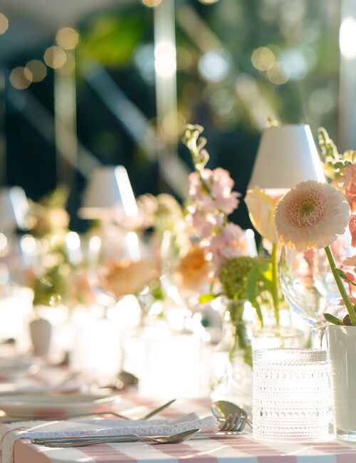 Elegant table setting with pink and white flowers, candles, and soft lighting, creating a warm and inviting atmosphere for an event.