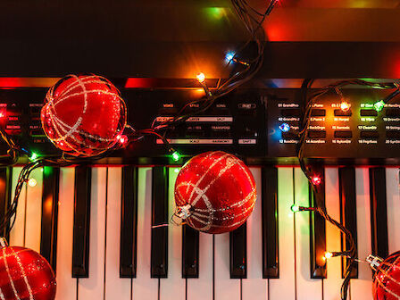 A keyboard decorated with red ornaments and colorful lights, along with sheet music placed on top.